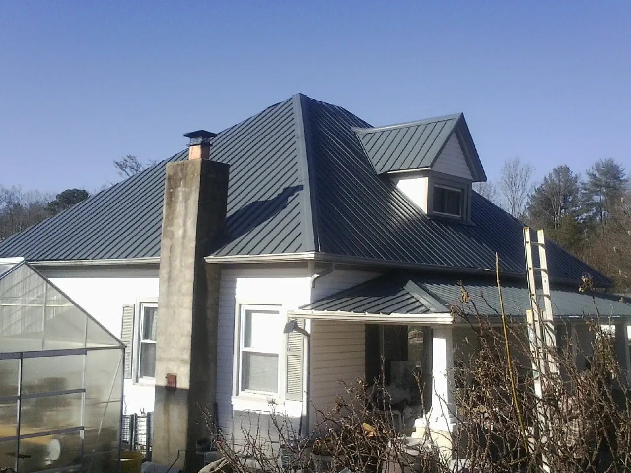Dark blue standing seam metal roof on a white farmhouse with dormer — Slate & Tile Roof Repair by Roofing Brothers in South Jordan