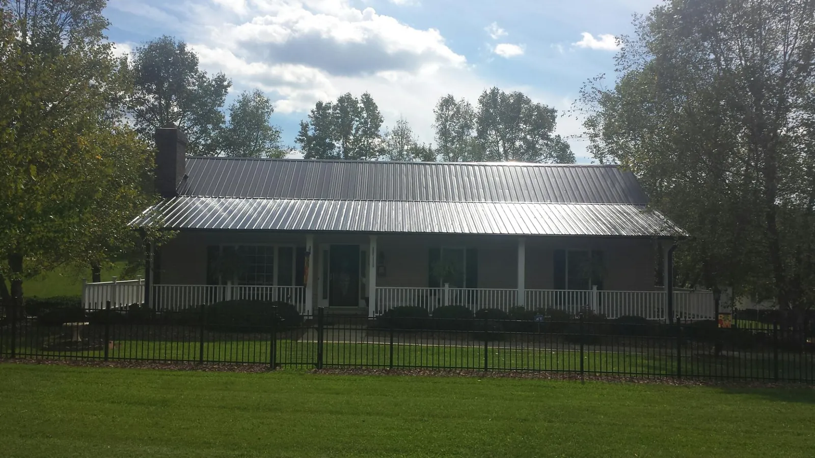 Gray metal roof on a brick ranch with a full width front porch — Gutter Guard Installation work by our crew in South Jordan