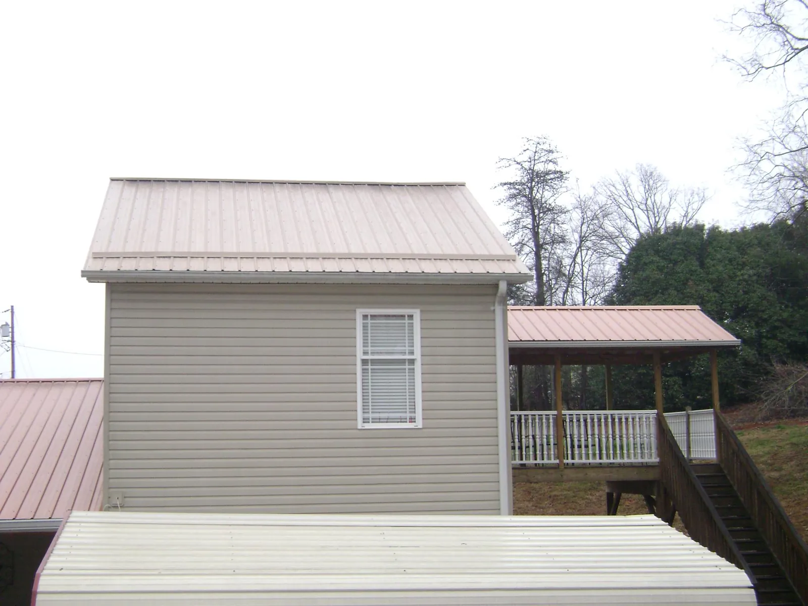 Tan metal roofs on a two story addition and attached porch, from a Roof Replacement job in South Jordan